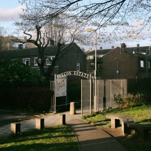 Path leading to a gate marked “Falcon Estate” on a sunny afternoon